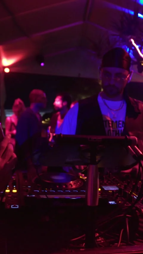 DJ Mixing Live at Open-Air Nightclub While Crowd Dances Under Neon Lights. Stock Footage 337902952
