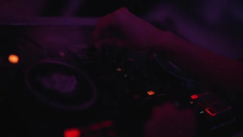 DJ mixing music on controller during live performance with moody lighting. Stock Footage 327339580