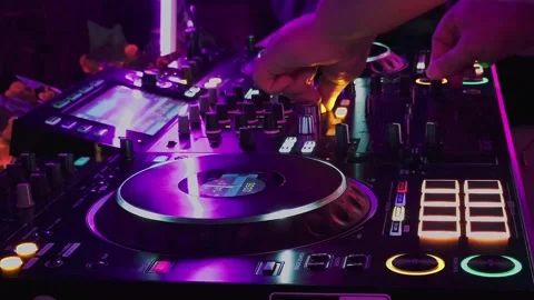 DJ mixing on professional controller with jog wheel and knobs under neon lights 库存影片 328961860