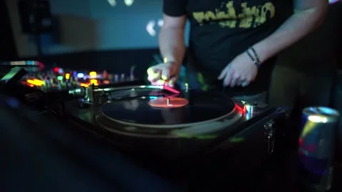 DJ mixing vinyl record on turntable and controller at nightclub booth during Stock Footage 331833711