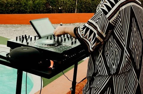 DJ performs at a poolside party during a warm summer evening with vibrant lig Stock Photos