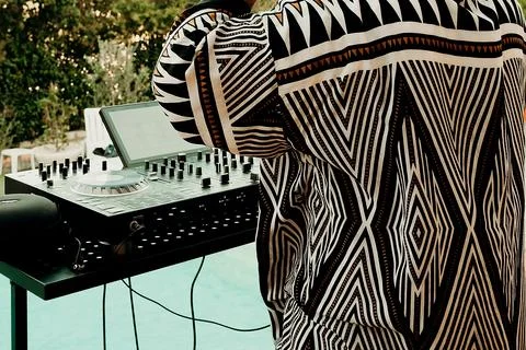 DJ performs at a poolside party during a warm summer evening with vibrant lig Stock Photos