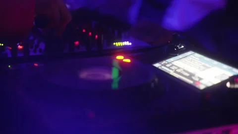 DJ playing with knobs on a mixing console at the party sorrounded by rgb 動画素材 237060288