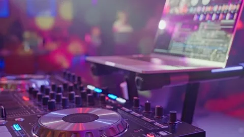 A DJ playing music on a mixer, controller, and turntable in a club setting Stock Footage 268020782