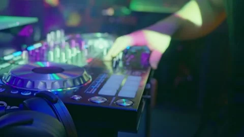 A DJ playing music on a mixer, controller, and turntable in a club setting Video stock 268478927
