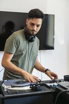 DJ playing the turntable while music plays in his studio Stock Photos