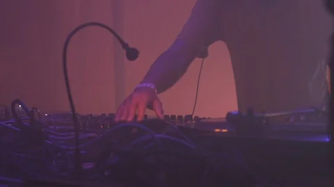 DJ playing vinyl records behind a turn table in a techno night club Stock Footage 117877660