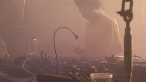 DJ playing vinyl records behind a turn table in a techno night club Stock Footage 117877839