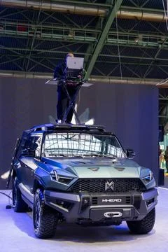 A DJ plays music from a control panel on the roof of a Dongfeng M-Hero SUV Photos