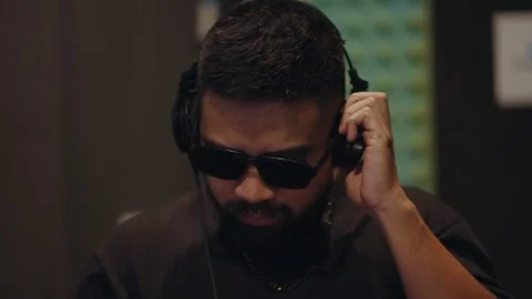 DJ practicing music mixing in a studio while wearing headphones Vídeo Stock 342930322