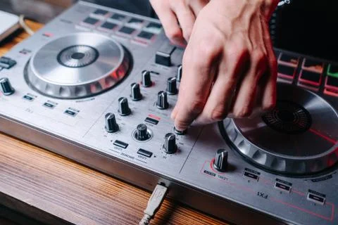 DJ is turning switches on controller close up, male hands visible Foto stock