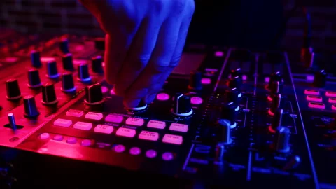 DJ twists knobs on mixing console behind his counter to set up rave in nightclub 스톡 동영상 172502674