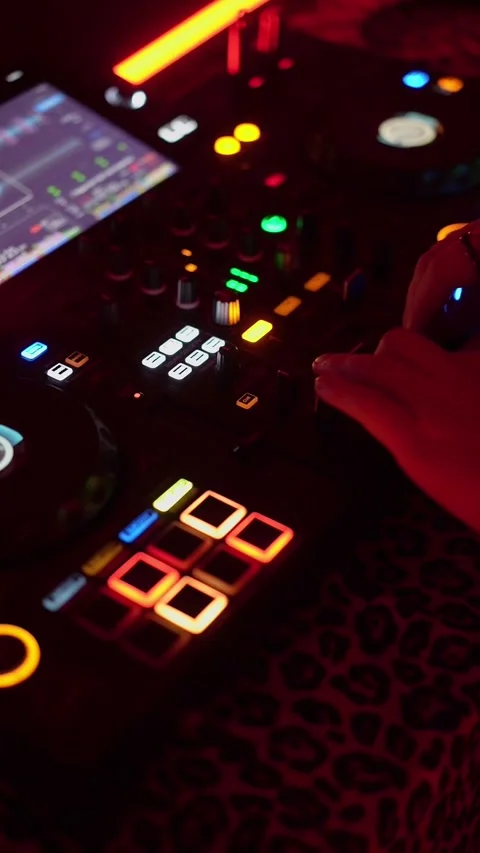 A DJ is using a mixer to blend music under vibrant lights in a nightclub 스톡 동영상 293760301
