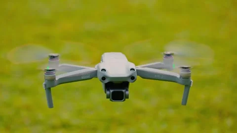 DJI Air 2S quadcopter, which floats in the air above the green grass in slow Stock-Footage 346364404
