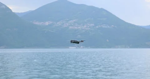 DJI Mavic 4 Pro drone flying over a calm lake with mountains. Copy space Stock Footage 333016573