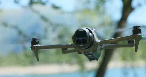 DJI Mavic drone hovering midair against blurred nature background. Close-up Stock Footage 339106006
