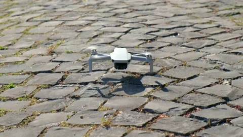 Dji Mavic Mini drone landing onto a flint-stoned floor and stop engines close vi Stock Footage 133553615