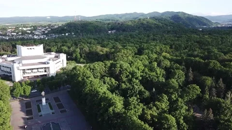 DJI Mavic Pro quadrocopter flight from a white building to a green forest Stock Footage 203849563