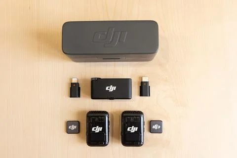 DJI MIC 2 microphone components arranged on wooden surface Stock Photos