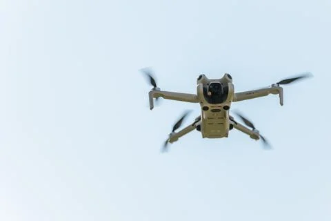 A DJI Mini 4 Pro drone hovers mid-air with propellers spinning Stock Photos
