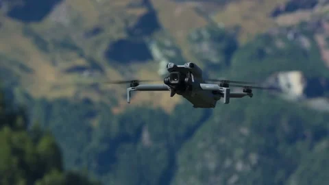 DJI Mini 5 Pro drone hovering with green mountain in background Stock Footage 341906752