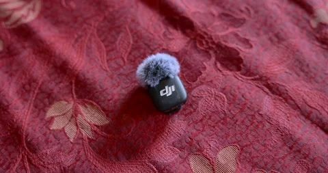 DJI Wireless Microphone With Windscreen On Red Textured Fabric Stock Footage 324943808