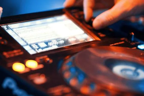 A DJ's hands are on a functional music console, looking for a song to play. Stock Photos