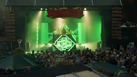 DJs perform electronic dance music on an outdoor stage for a crowd in Nemoland Stock Footage 344984043