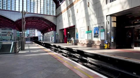 DLR train approaching the public transport platform at Canary Wharf station, a Stock Footage 336557951