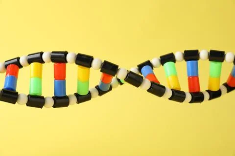 DNA structure model on yellow background, closeup Stock Photos