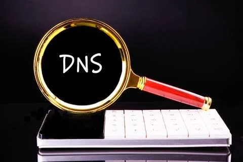 DNS Domain Name Server through a magnifying glass on a calculator on a blac.. Stock Photos