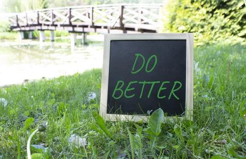 Do Better symbol. Do Better black chalk blackboard. Beautiful meadow backgrou Stock Photos
