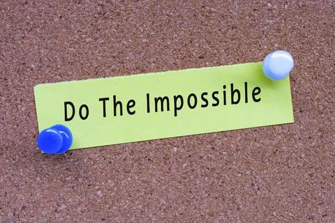 Do the impossible words on stick note and pinned to a cork notice board. Foto stock