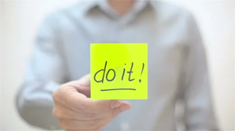 Do it. A man sticks a note on transparent screen Stock Footage