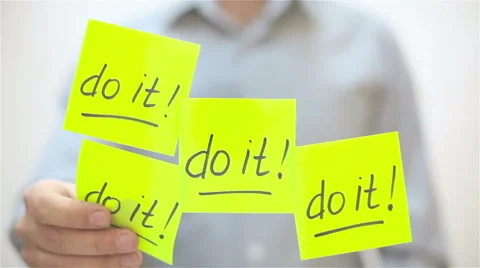 Do it. A man sticks a note on transparent screen Stock Footage 68088748