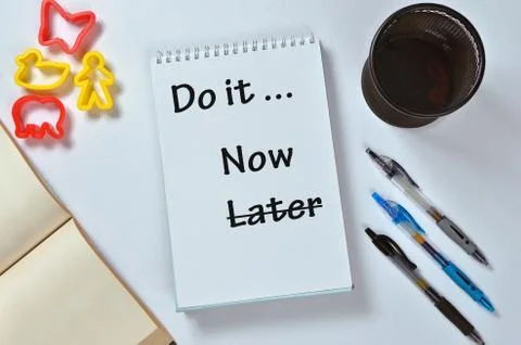 Do it now not later text on notepad with office accessories. Business motivat Stock Photos