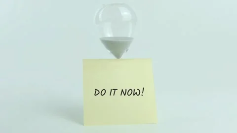 Do it Now written on yellow sticky note placed on hourglass on white Stock Footage 313475324