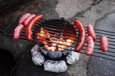 A Do it yourself backyard BBQ grill in  a bucket with sausages and potatoes Stock Photos