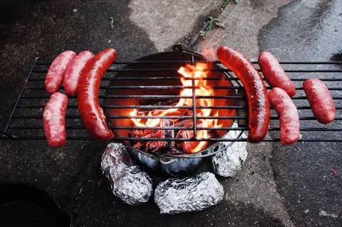 A Do it yourself backyard BBQ grill in  a bucket with sausages and potatoes Stock Photos