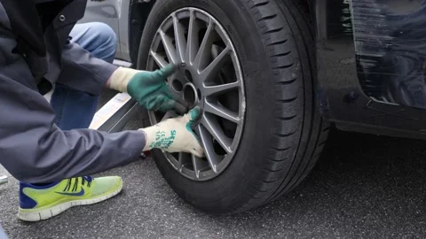 Do it yourself man changes tires on his car, and tighten with a cross 스톡 동영상 152943186