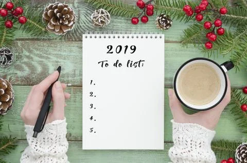 To do list 2019. Flat lay girl hand holding pen and coffee, on green wooden Stock Photos