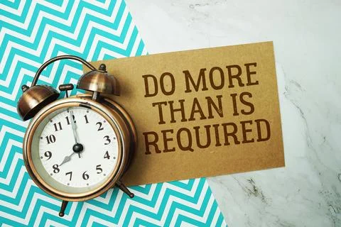 Do More Than Is Required text written on paper card with alarm clock on mar.. Stock Photos