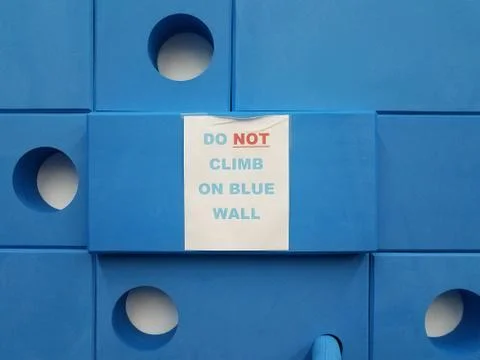 Do not climb on blue wall sign and foam blocks Stock Photos