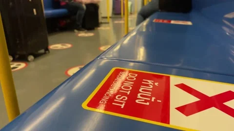 "DO NOT SIT SOCIAL DISTANCING" sticker on blue seat on moving train Stock Footage 183549718