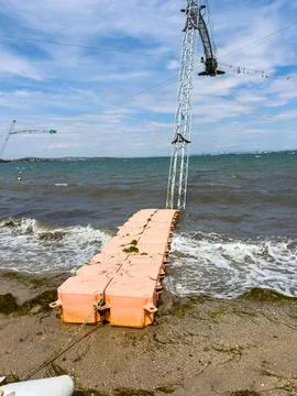 Dock constructed from floating materials on a beach with calm waves and equ.. Stock-Fotos
