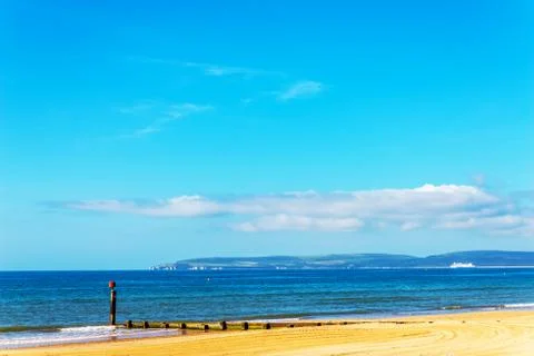 Dock pilings on a sandy beach, blue ocean and yellow sand, sunny hot day Stock Photos