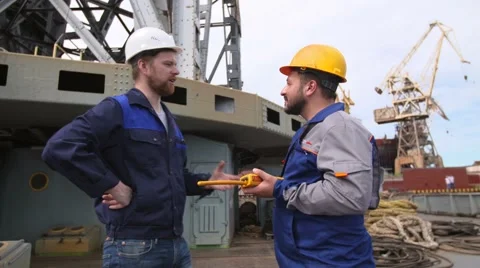 Dock worker and engineer have serious talk, then laugh and give high five in Stock Footage
