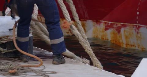 Dock worker pulls mooring ropes along wet concrete pier Stock Footage 320902876
