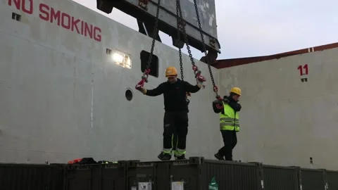 Dock workers attaching hooks and chains to steel containers Stock Footage 233684093