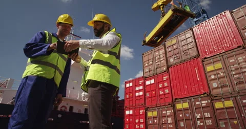 Dock workers discuss logistics at the harbor amidst shipping industry activity.  Stock Footage 54930440